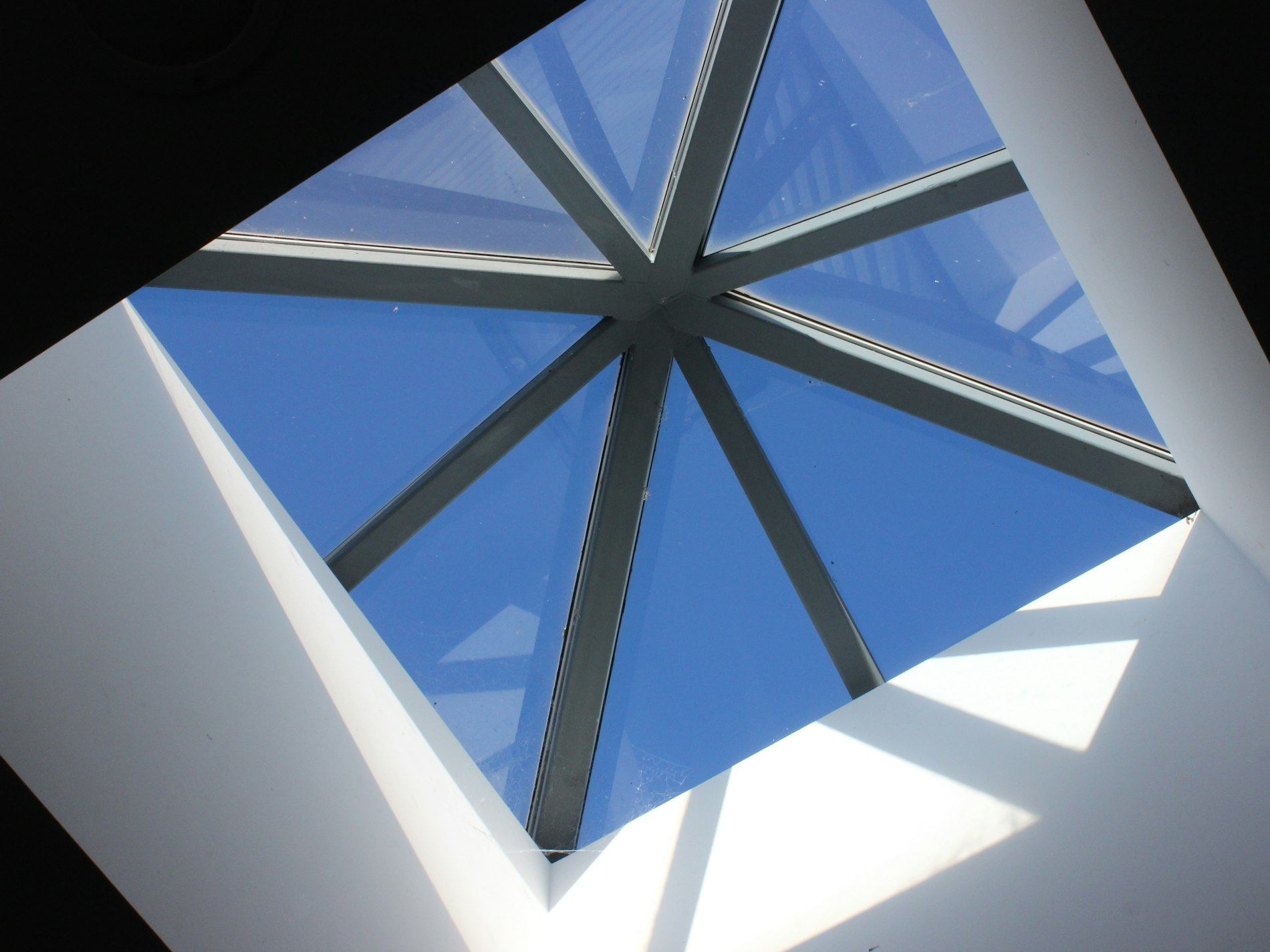 Glass skylight with geometric frame against blue sky