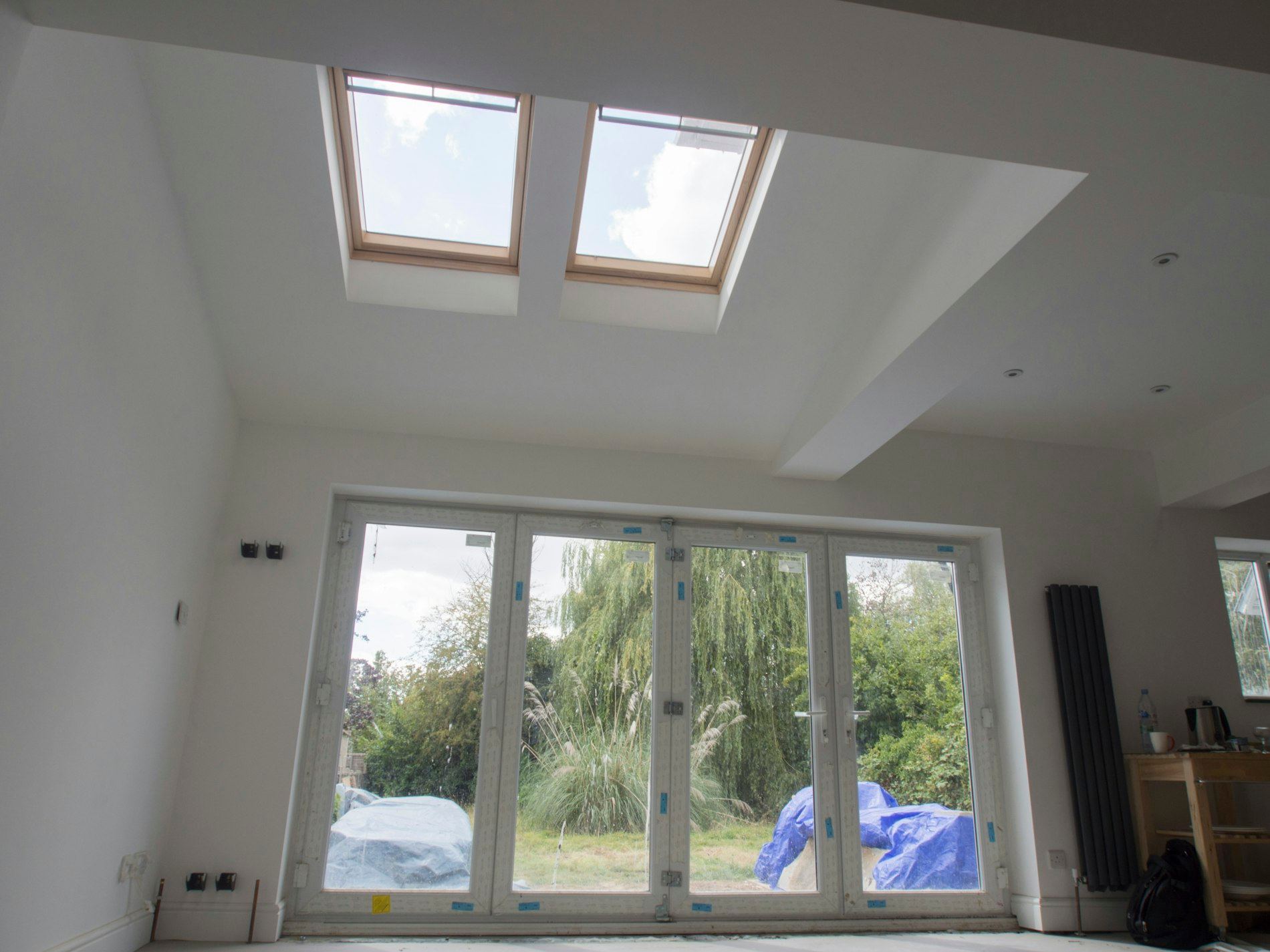 Bright room with two roof skylights and bifold doors opening onto a garden.